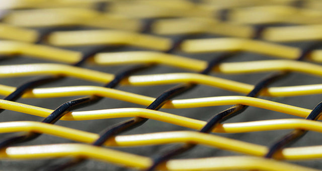 Close-up of yellow and black tennis racket strings woven in a cross pattern.