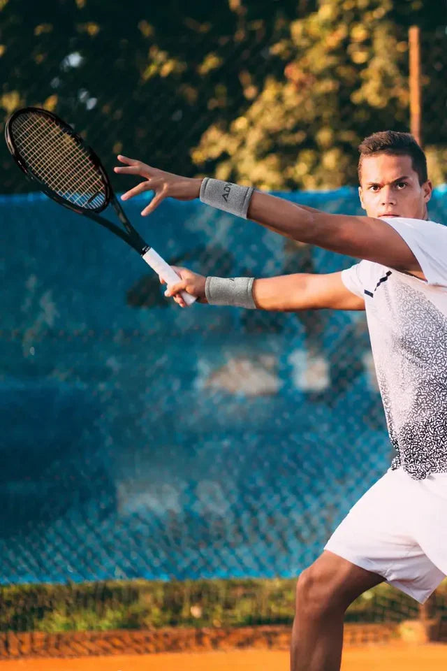 Tennis wristbands featured on a male player in action pose wearing a black shirt and holding a racquet.