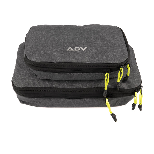 Two ADV grey packing cubes with black zippers and neon green pull tabs.