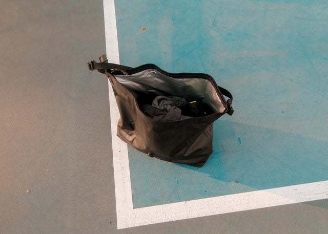 Black ADV Air Vault Tote open on a tennis court, holding post-match gear.