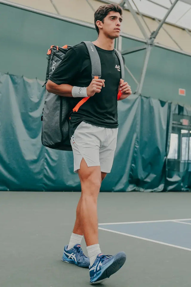 pickleball equipment carried by a male athlete wearing a backpack-style ADV tennis bag while walking on an indoor court
