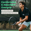Tennis player ready with racquet gripped in white FeltTac overgrip on outdoor court.