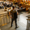 Person wearing the black RPM Pickleball Bag Pro backpack in a busy cafe lobby.
