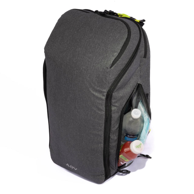 Gray tennis bag with side compartments holding bottles, featuring a modern design and green zipper accents.