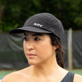 Person wearing a black perforated ADVantage tennis cap on an outdoor court.