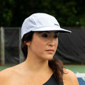 White perforated ADVantage tennis cap worn on court, showing side ADV logo and mesh venting.