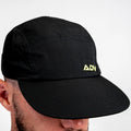 Person wearing black ADVantage tennis cap with volt green ADV logo, side profile view.