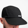 Black ADVantage tennis cap worn on-model, side view showing perforated panels and white ADV logo.