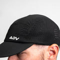 Black ADVantage tennis cap worn on-model, showing white logo and laser-cut side ventilation.