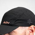 Black ADVantage tennis cap with lava-orange logo and perforated side panels, worn on-model.