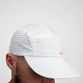 White ADVantage tennis cap with laser-cut side vents and coral logo, worn side view.