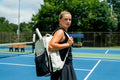 Player carries the cream and black ADV Flex tennis backpack with racket on a court.