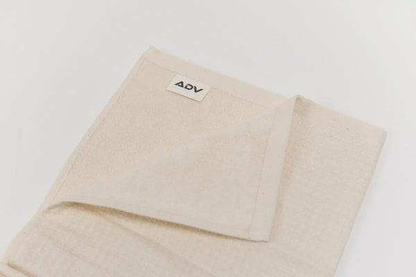 Folded natural cotton ADV court towel showing dual-sided waffle and smooth textures.